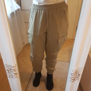 BikBok satinbyxor i cargomodell - Nyskick, anv en gång ~ Kaki/mörkbeige, kraftigt satintyg. Fickor & dold dragsko/knytning i midjan. ~ STOR rensning & erbj i min shop ~