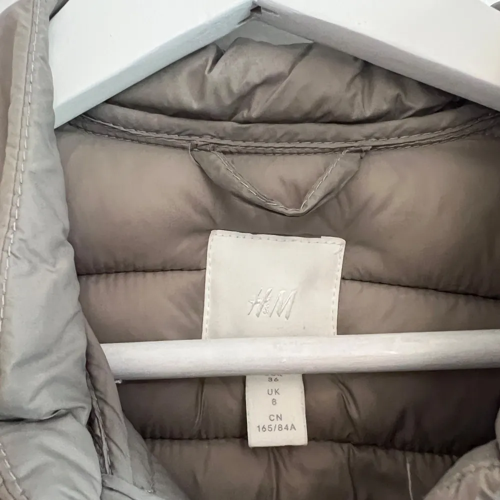 Säljer en snygg beige pufferjacka från H&M. Jackan är perfekt för höst och vår med sin quiltade design och långa ärmar. Den har en stilren look med knappar framtill. Superbra skick och redo för nya äventyr!. Jackor.