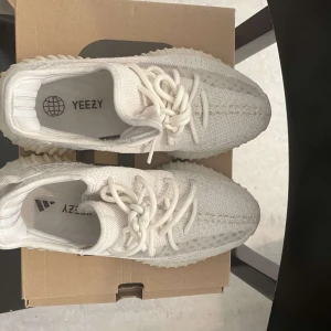 Vita Adidas Yeezy sneakers - Säljer ett par vita Adidas Yeezy sneakers i nyskick. De har en stickad ovandel med snörning och en bekväm, ribbad sula. Perfekta för både vardag och fest!