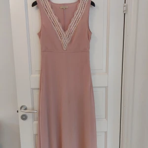 Klänning VILA - Fin klänning i mycket bra skick (sparsamt använd). Färg gammelrosa med spetsdetaljer. Dragkedja i sidan. Storlek L. Innerkjol ger fint fall. 