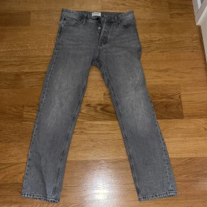 Grå jeans från Jack & Jones w29 L32 - Säljer ett par grå jeans från Jack & Jones med en relaxed fit. De har en klassisk femficksdesign och knappgylf. Perfekta för en avslappnad stil.