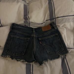 Jeansshorts från Levis - Snygga jeansshorts från Levi's med fransiga kanter och klassisk femficksdesign. Perfekta för en avslappnad stil. Mörkblå denim med slitna detaljer ger en cool look.