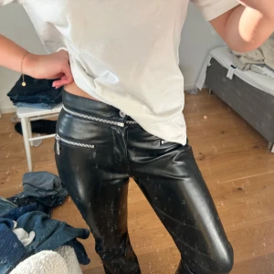 Svarta skinnbyxor med dragkedjor - Snygga svarta skinnbyxor med coola dragkedjedetaljer vid fickorna. Byxorna har en straight passform och är perfekta för en edgy look. 🥰