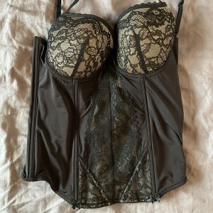 Svart korsett med spetsdetaljer - Elegant svart korsett med vackra spetsdetaljer och vadderade kupor. 