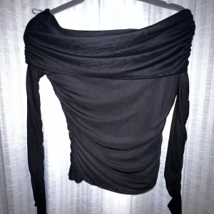 Svart offshoulder topp - Snygg svart offshoulder topp med långa ärmar och draperad design. Perfekt för en stilren look. Från gina storlek M men väldigt stetchig så kommer sitta bra på S också. Använd 1 gång. Diskuterar gärna pris vid snabb affär.