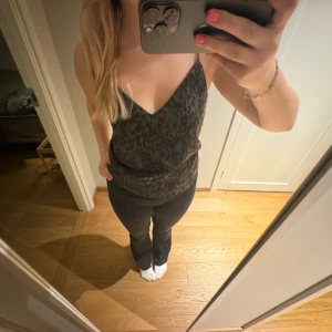 Leopardmönstrad linnetopp - Snygg leopardmönstrad linnetopp i grönt och svart. Toppen har en v-ringad design och är ärmlös, perfekt för en trendig look🩷.