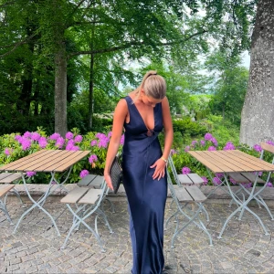 Marinblå balklänning (långklänning) - INTRESSEKOLL!?!? Tänkte kolla om någon är intresserad av den här otroligt eleganta mörkblå långklänningen med djup v-ringning och öppen rygg. Klänningen har en figurnära passform och är perfekt för festliga tillfällen, ex. balen som snart äger rum. Klänningen är endast använd en gång, är i fint skick och köptes för strax under 3000kr + fraktkostnad & tull. Klänningen är även slutsåld helt på hemsidan i denna storlek. (Jag är 175cm på bilden)