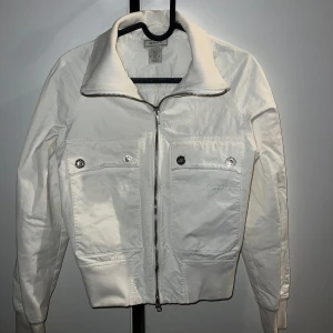 Vit jacka från Gant - Snygg vit jacka från Gant med dragkedja och två framfickor med knappar. Vintage stil