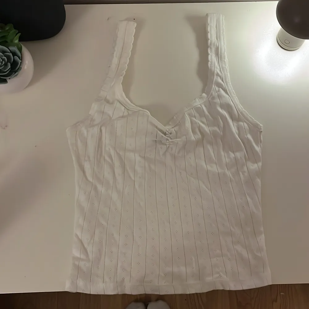Säljer en söt vit ribbad linnetopp från Gina Tricot. Toppen har ett diskret mönster och breda axelband. Perfekt för varma dagar eller som ett lager under en tröja. Aldrig använd men ingen lapp kvar . Yläosat.