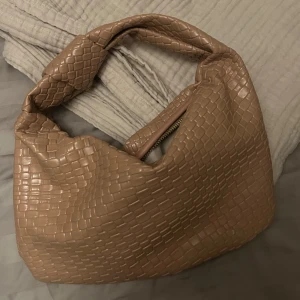BEIGE AXELVÄSKA FLÄTAT MÖNSTER - Snygg beige axelväska med ett flätat mönster och dragkedja. Mycket bra skick! Säljer även en svart