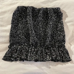 Svartvit kjol från Pull&Bear - Snygg svartvit kjol från Pull&Bear med elastisk midja och volangdetalj i nederkant. Perfekt för en stilren look med sitt abstrakta mönster. Tillverkad i ett lätt och bekvämt material.