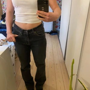 Svarta lågmidjade jeans med gullig detalj - Svarta lågmidjade stretchiga jeans med en super söt blomma på ena bakfickan!