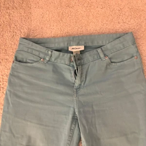 Ljusa blå byxor från Monki - Snygga ljusblå byxor från Monki med bootcut-stil. De har en klassisk femficksdesign och stängs med dragkedja och knapp. Perfekta för en avslappnad look.