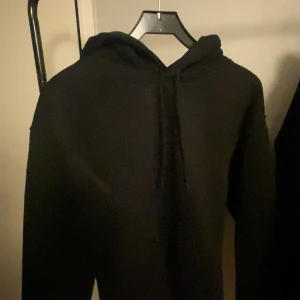 Svart och grå hoodie - Säljer två hoodies i olika färger. Den ena är svart och den andra är grå. Båda har en klassisk design med huva och dragsko samt en stor ficka framtill. Perfekta för en avslappnad stil. Storlek xs på båda men skulle säga att dem liknar s 