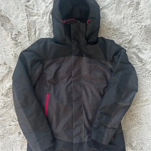 Svart vindjacka från Everest - Säljer en svart/mörkgrå vindjacka från Everest med rosa detaljer. Jackan har en justerbar huva och dragkedja framtill. Perfekt för blåsiga dagar och håller dig skyddad mot väder och vind. Hör av dig vid frågor eller fler bilder! 