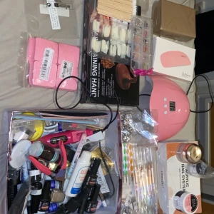 Nagelvårdspaket med LED-lampa och tillbehör - Stort nagelvårdspaket med rosa LED-lampa, gelpolish, nagelkonstpennor, akrylpulver och glitter. Inkluderar även nagelfilar, buffertar, nagelformar och rhinestones för dekoration, nagel lim m.m. Perfekt för att skapa egna nageldesigner hemma. Vissa saker är använda men de mesta är oanvänt! Allt eller inget 