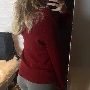 Röd tröja från Busnel - Snygg röd tröja från Busnel med v-ringning. Perfekt för kyligare dagar och ger en stilren look. Tillverkad i Frankrike.