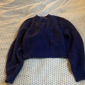Mörkblå stickad tröja från Weekday - Säljer en superfin mörkblå stickad tröja från Weekday. Den är croppad och har en mysig, ribbad textur som är perfekt för höst och vinter. Tröjan har långa ärmar och är i storlek XS. Perfekt för att hålla sig varm och stilren under kyliga dagar!