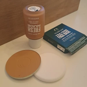 Foundation och puder från The Body Shop - Säljer en foundation och ett puder från The Body Shop. Foundationen heter Fresh Nude och kommer i en smidig flaska med 30 ml innehåll. Den har en naturlig finish och är berikad med aloe vera. Pudret är Tea Tree Face Base, perfekt för att hålla huden matt och fräsch. Båda produkterna är i nyansen Tan 2W och är veganska.