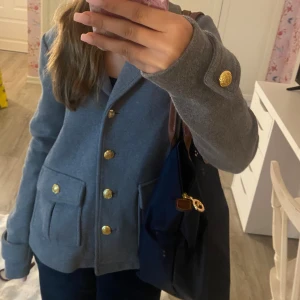 Grå kappa med knappar  - Säljer denna gråa kappan med guldiga knappar. Den är i storlek XS och från Lindex 💗 Den har tyvärr en knapp som har lossnat (kan fixa bättre bilder), men annars är den i väldigt bra skick💗