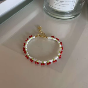 Färgglatt pärlarmband - Säljer ett superfint armband med små pärlor i vitt, rött och grönt. Armbandet har en justerbar kedja i guld som gör det enkelt att anpassa storleken. Perfekt för att liva upp vilken outfit som helst! 🌟