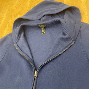 Mörkblå hoodie från Polo Ralph Lauren - Säljer en snygg och bekväm mörkblå hoodie från Polo Ralph Lauren. Den har en dragkedja framtill och en klassisk huva. Perfekt för både höst och vinter, och den är i nyskick. Passar perfekt för en avslappnad stil eller när du bara vill mysa hemma. 