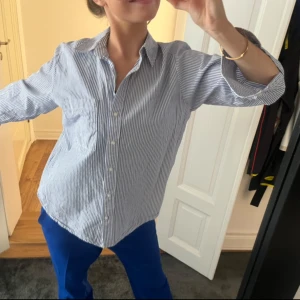 Blå-vit randig skjorta - Blå randig skjorta. Passar året om på sommarn som vanligt men även på hösten med en mysig stickad tröja.