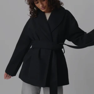 Svart kappa med med knytskärp - Kappa svart i nyckick från gina tricot säljer på grund av att jag tog för lång tid att returnera. Kort kappa med knytskärp i midjan. Den har lång ärm och fickor i sidorna. Fodrad