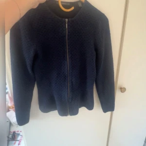 Mörkblå jacka med dragkedja - Säljer en snygg mörkblå korta med dragkedja framtill. Koftan har en enkel och stilren design med långärmade ärmar. Perfekt för både vardag och lite finare tillfällen. Passar bra till höst och vår!