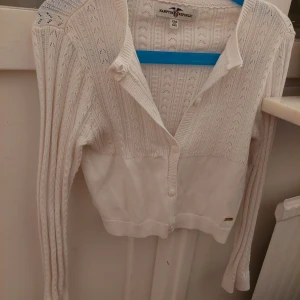 Vit stickad kofta från Hampton Republic - Säljer en superfin vit stickad kofta från Hampton Republic. Den har ett snyggt hålmönster och knappar framtill. Perfekt för både vår och höst, och den är i nyskick. Passar perfekt till både vardag och fest! 🌟