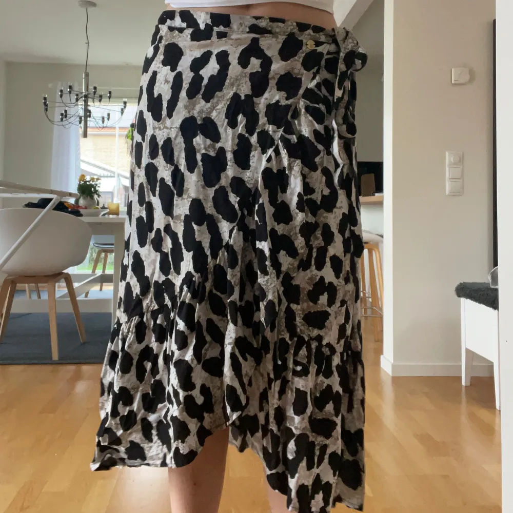 Säljer en superfin leopardmönstrad omlottkjol i svart och beige. Kjolen har en knytning i midjan och en volangdetalj längst ner. Aldrig använd, storlek 38. Från Pernilla Wahlgren collection. . Kjolar.