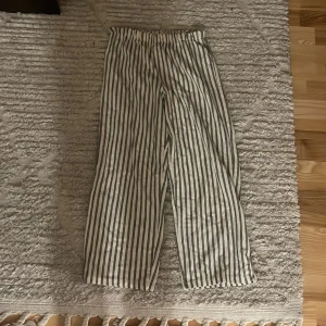 Randiga byxor - Säljer ett par randiga byxor i vitt och svart. De har en loose passform och är perfekta för en avslappnad stil. Byxorna är elastiska i midjan för extra komfort. Perfekta för vår och sommar!