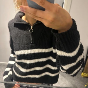 Svart och vit randig stickad tröja - Säljer en supermysig svart och vit randig stickad tröja med dragkedja och hög krage. Perfekt för kyliga dagar och ger en skön och avslappnad look. Passar perfekt till både jeans och kjol! Skriv för fler bilder eller frågor💗