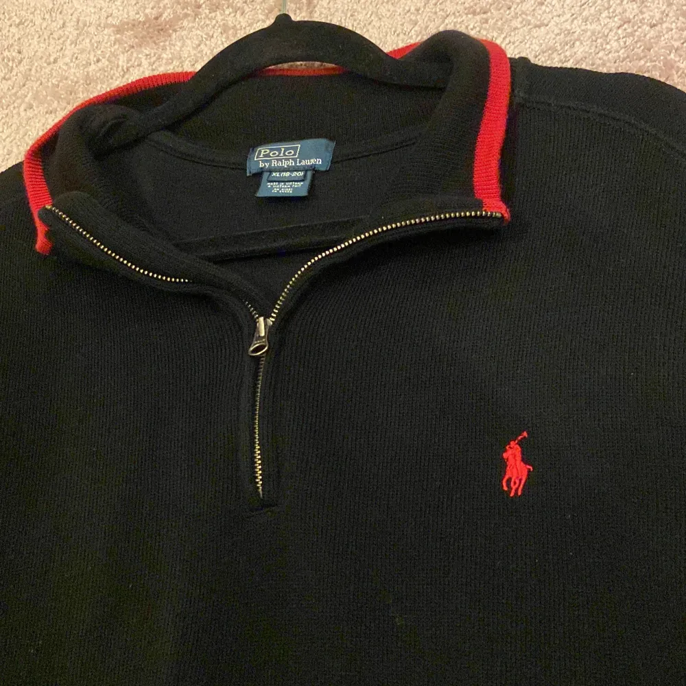 Ralph Lauren Quarter Zip Svart tröja med röd broderad Ralph Lauren logga. Skick: 8/10, Inga skador eller liknande! Storlek: XL 18-20 barn = strl M vuxen. Sitter lite stort på mig som är 173 cm, 60 kg då jag föredrar annan passform. Äkta såklart✅ Mvh!. Tröjor & Koftor.