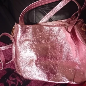 Rosa glittrig axelväska från Mia Tomazzi - Säljer en superfin rosa glittrig axelväska från Mia Tomazzi. Väskan har en praktisk dragkedja och är perfekt för att lysa upp vilken outfit som helst. Den är i mycket bra skick och gjord av äkta läder. Perfekt för festliga tillfällen! ✨