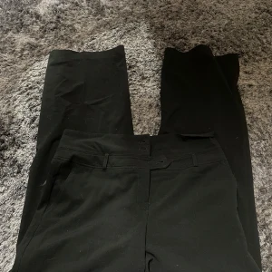 Svarta kostymbyxor från KappAhl - Säljer ett par stilrena svarta kostymbyxor från KappAhl i storlek S. De är i bra skick och perfekta för både jobb och fest. Byxorna har en klassisk passform med hög midja och raka ben. Ett måste i garderoben för en elegant look!