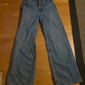 Blå jeans från H&M Divided - Säljer ett par blå jeans från H&M Divided i storlek XS. De har en loose fit och är perfekta för en avslappnad stil. Jeansen är i bra skick och har en klassisk femficksdesign. Perfekta för både vardag och fest!