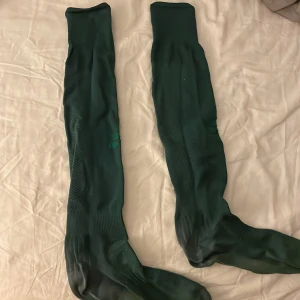 Gröna fotbollstrumpor - Säljer ett par långa gröna knästrumpor i bra skick från Bajen.Perfekta för träning eller vardagsbruk. De är elastiska och bekväma, vilket gör dem idealiska för både sport och avslappnade dagar. 