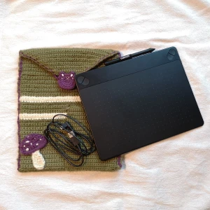 Wacom ritplatta med ett virkat fodral - Wacom intuos art ritplatta i använt men bra skick; den är fullt fungerande. Det finns märken på områden av plattan där pennan har använts mycket på. En fläck finns också på baksidan (se bild 3). Förutom pennan så kommer det med 2 extra pen tips i facket på baksidan. Ett virkat fodral kommer med på köpet. Är fodralet oönskat så säg till men priset blir samma utan. Fodralet är handgjort av en nybörjare(jag) så fel kan finnas om man stör sig på det.  Den väger också en del. Pm för fler bilder.