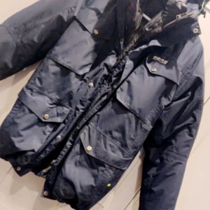 Blå jacka från 8848 Altitude  - Säljer en snygg blå jacka från 8848 Altitude. Den har en cool design med flera fickor och knappar. Perfekt för höst och vinter, Jackan har en dragkedja och är i mkt bra skick. Strl S