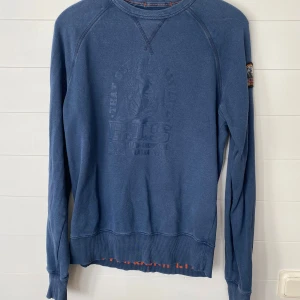 Blå fleece tröja från Parajumpers - Säljer en snygg blå tröja från Parajumpers i storlek S. Den har ett coolt märke på ärmen och är perfekt för kyliga dagar. Tröjan är i bra skick. Perfekt för både vardag och äventyr! 💙