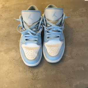Nike Air Jordan 1 Low - Dessa fantastiskt sköna skor säljs nu med ett fåtal använda gånger. Modellen heter: ”Nike Air Jordan 1 Low, Ice blue Aluminum” Storlek 42,5 är det. Skick på dojorna är 9/10. Köpta i butiken Pardon My Kicks. 