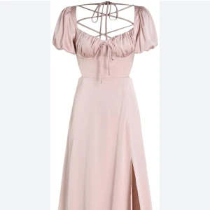 Ljusrosa långklänning med puffärmar - Säljer en superfin ljusrosa långklänning med puffärmar och en snygg slits. Klänningen har en unik snörning i ryggen och är gjord i ett glansigt material som ger en lyxig känsla. Perfekt för sommarens fester eller en romantisk kväll. Nypris 420kr