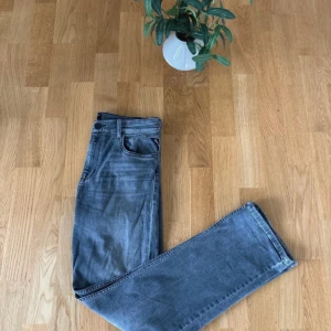 Grå jeans från Replay - Snygga grå jeans från Replay med klassisk femficksdesign. De har en rak passform och är tillverkade i ett slitstarkt denimtyg. Perfekta för en avslappnad stil.
