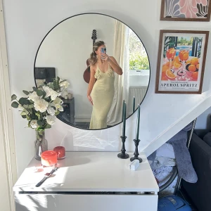 Gul stickad klänning med blommiga detaljer - Säljer en elegant beige stickad klänning med vackra blommiga detaljer vid axelbanden. Klänningen har en tight passform och är ärmlös. Den är gjord i ett mjukt stickat material som ger en bekväm känsla. Öppen rygg och lång. Jag är 168cm och den slutar ungefär vid ankel/fotleden. Ny aldrig använd, säljer då jag inte tycker jag passar i den.