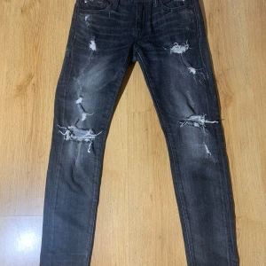 Svarta Ralph luarean jeans  - Snygga svarta jeans med slitningar och hål för en trendig look. De har en skinny passform och är perfekta för en avslappnad stil. Jeansen har klassisk femficksdesign och är tillverkade i denim. Märke Ralph luarean storlek 158-164
