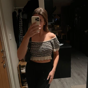 Randig offshoulder topp - Snygg randig offshoulder topp i svart och beige. Toppen är croppad med volangdetaljer vid nederkanten. Aldrig använt🖤