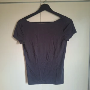 Mörkgrå topp från Gina Tricot - Säljer en mörkgrå topp från Gina Tricot i storlek M. Toppen har korta ärmar och en djup urringning i ryggen. Perfekt för en stilren look. Knappt använd köpte fel storlek!