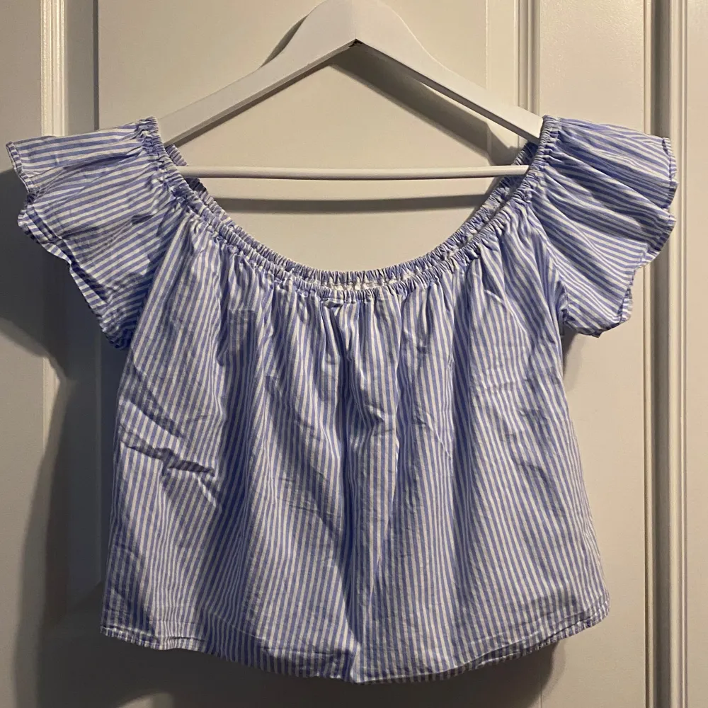 Säljer en söt blå- och vitrandig offshoulder topp från Zara. Toppen har korta ärmar med volangdetaljer och en luftig passform. Inunder sitter ett ”fastsytt linne” med resår nedtill . Totala längd från rakt framtill är 35 cm ( sträckt tyg) Perfekt skick! . Puserot.