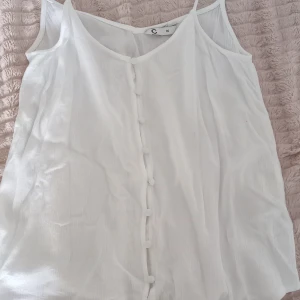 Vit ärmlös blus med knappar - Säljer en stilren vit ärmlös blus med knappar framtill. Från Cubus i storlek 34.